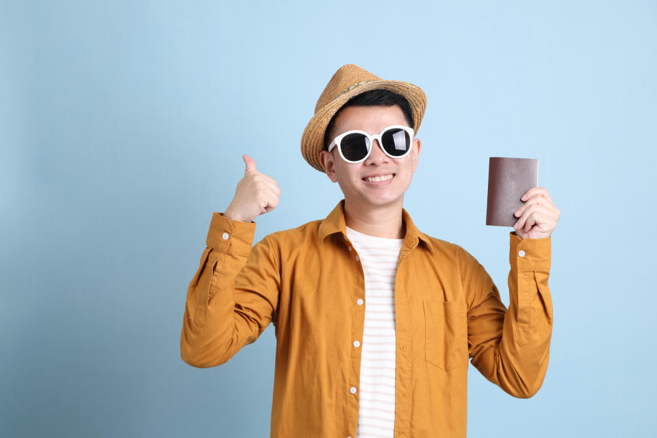 The Asian LGBTQ man with yellow shirt standing on the blue background.