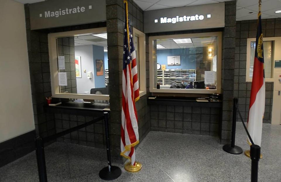 A magistrate waits at a window to perform his duties at the criminal magistrate office at Mecklenburg County Arrest Processing Center on Tuesday, March 31, 2020.