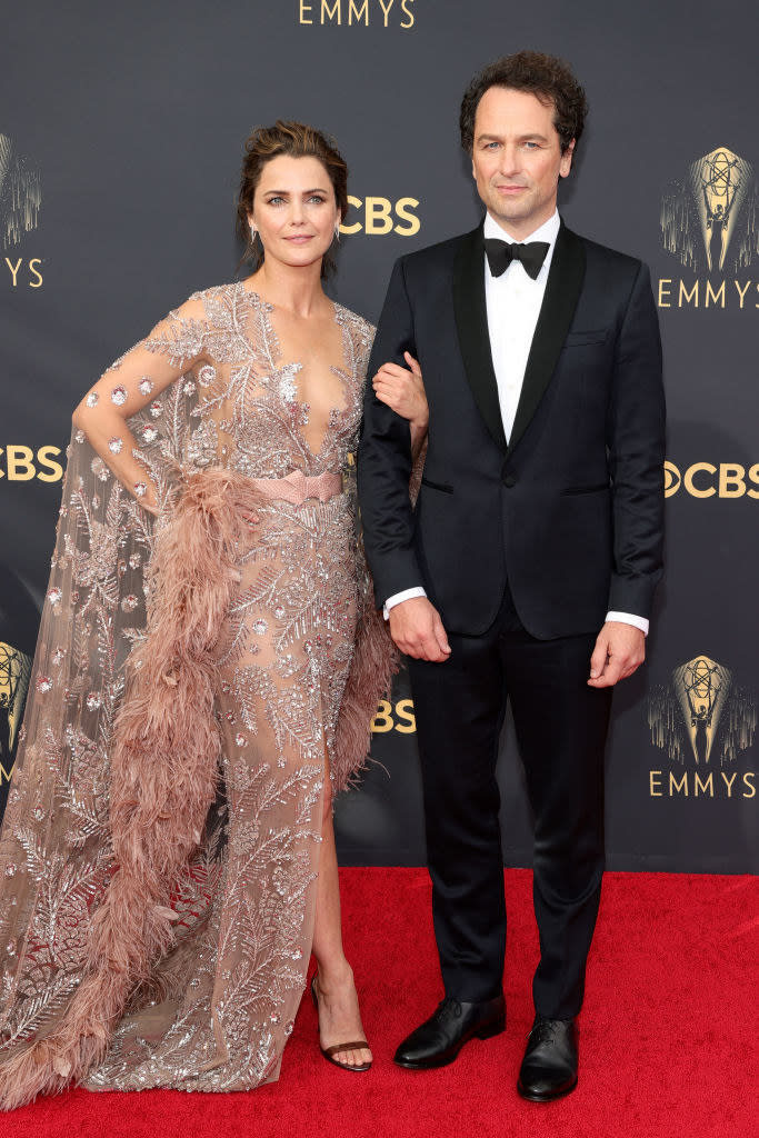 Keri Russell wears a crystal encrusted gown with a long train and Matthew Rhys wears a dark suit