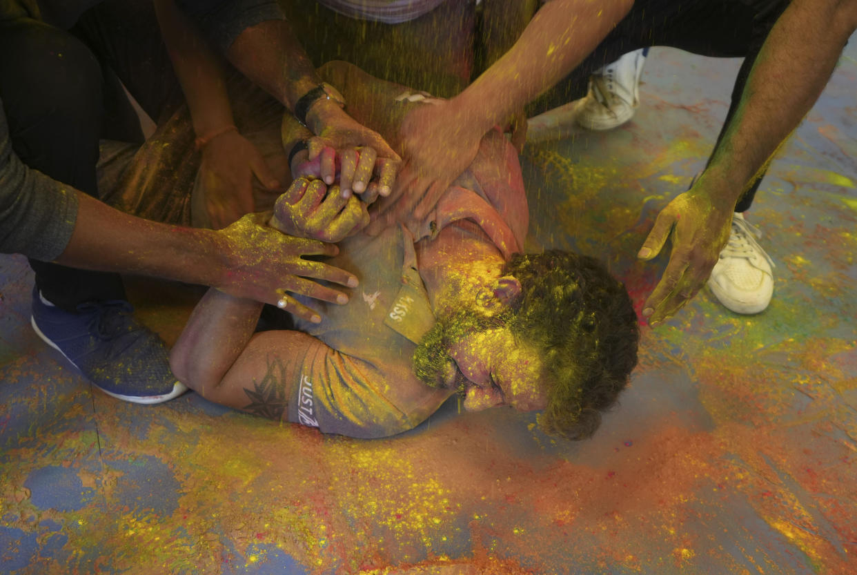 People put colour powder to their friend to celebrate Holi festival, in Prayagraj, in the northern Indian state of Uttar Pradesh, India. Tuesday, March 7, 2023. Millions of Indians on Wednesday celebrated the ''Holi" festival, dancing to the beat of drums and smearing each other with green, yellow and red colors and exchanging sweets in homes, parks and streets. Free from mask and other COVID-19 restrictions after two years, they also drenched each other with colored water. (AP Photo/Rajesh Kumar Singh)