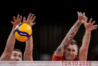 Maxim Mikhaylov, of the Russian Olympic Committee, left, and his teammate Ivan Iakovlev, of the Russian Olympic Committee, block a ball during the men's volleyball semifinal match between Brazil and Russian Olympic Committee at the 2020 Summer Olympics, Thursday, Aug. 5, 2021, in Tokyo, Japan. (AP Photo/Manu Fernandez)