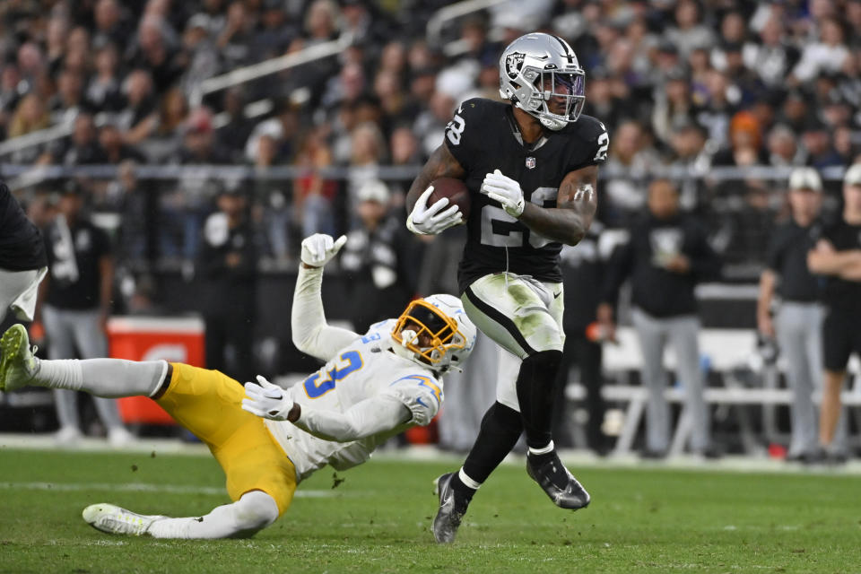 Las Vegas Raiders running back Josh Jacobs (28) carries past Los Angeles Chargers safety Derwin James Jr. (3) during the second half of an NFL football game, Sunday, Dec. 4, 2022, in Las Vegas. (AP Photo/David Becker)