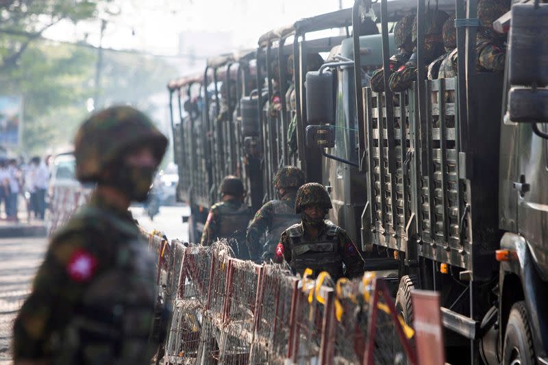 FILE PHOTO: FILE PHOTO: Soldiers stand next to military vehicles as people gather to protest against the military coup, in Yangon