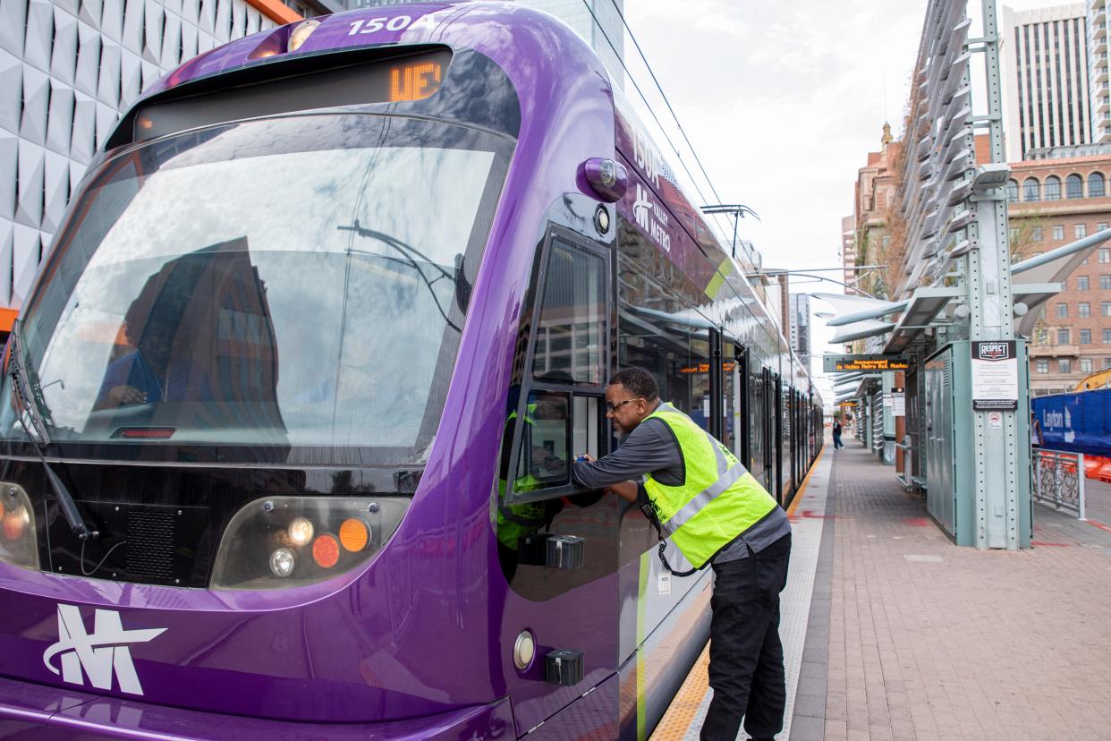 Rod Evans, a valley metro line controller, talks with a train conductor at a light rail stop in downtown Phoenix on July 21, 2022.