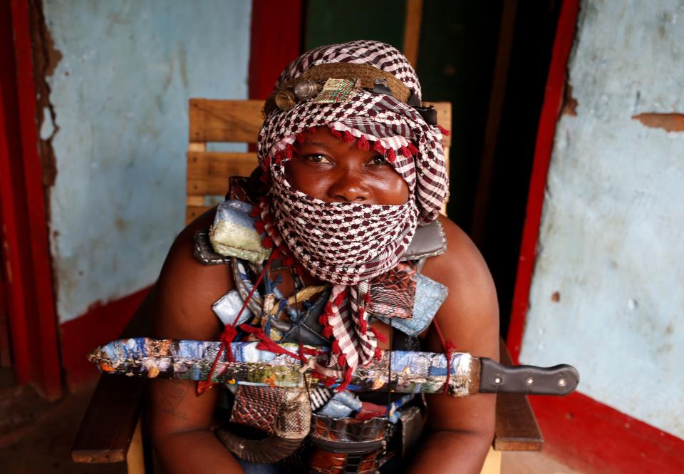A masked female member of the anti-balaka, a Christian militia, sits in the village of Zawa