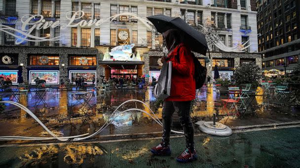 PHOTO: A man walks under the rain with his shopping bags as people visit a department store during the holiday season in New York City, Dec. 15, 2022. (Eduardo Munoz/Reuters)