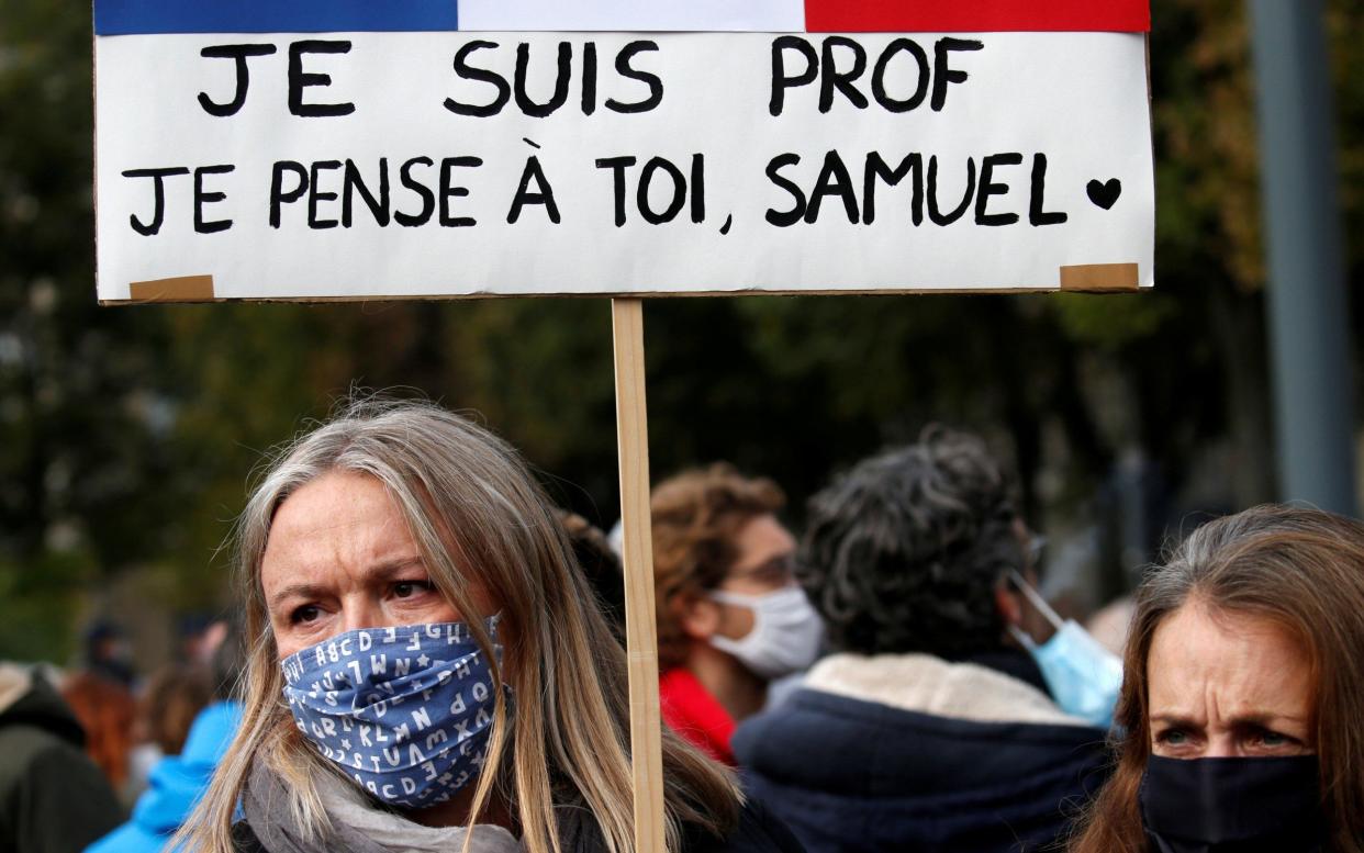 A female protester with a sign reading "I am a teacher, I think of you, Samuel." - Pascal Rossignol/Reuters