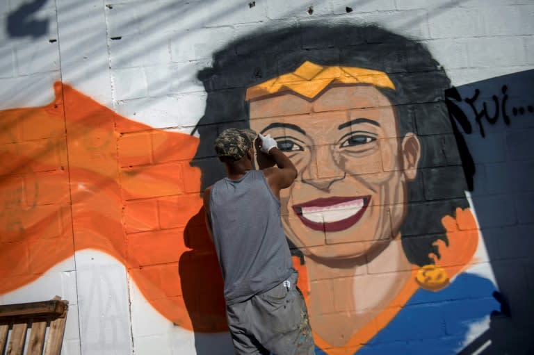 A man paints a mural depicting slain Brazilian human rights activist and politician Marielle Franco as Wonder Woman