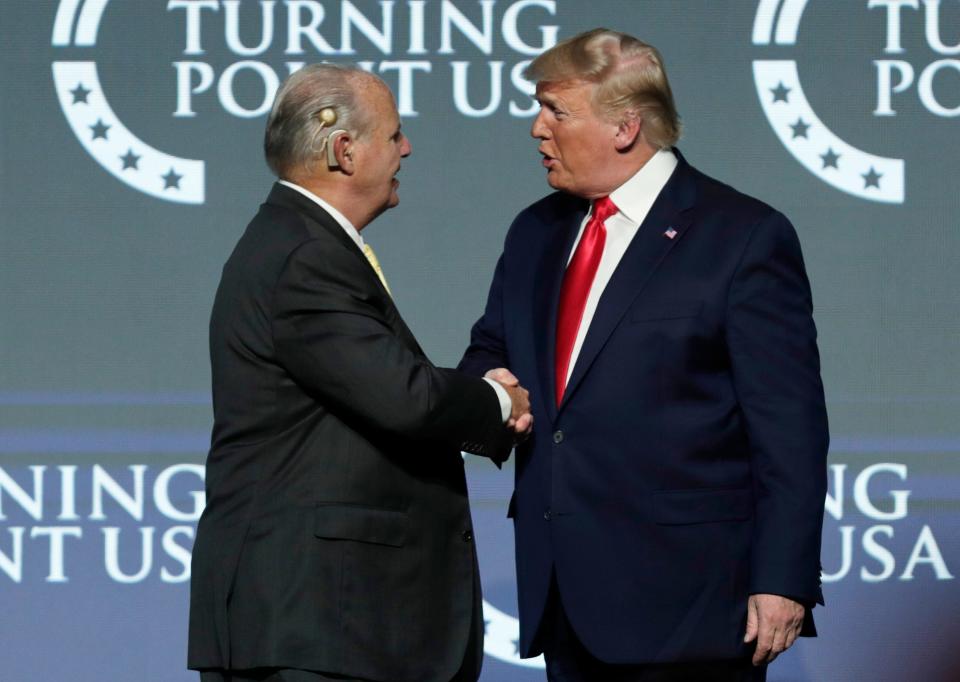 In this file photo, Rush Limbaugh, left, shakes hands with President Donald Trump as he introduces Trump at the Turning Point USA Student Action Summit at on Dec. 21, 2019, in West Palm Beach, Florida. Limbaugh died of lung cancer on Wednesday, Feb. 17, 2021, four weeks after Trump left office. (AP Photo/Luis M. Alvarez, File)