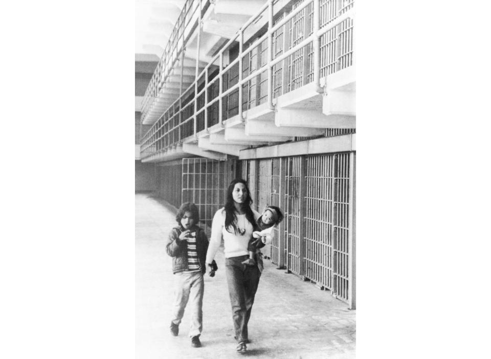 In this photo taken March 26, 1970, Eldy Bratt, 33, walks down the lonely corridor of a cell block on Alcatraz with her son Peter Bratt, left, and one of her daughters in San Francisco. The week of Nov. 18, 2019, marks 50 years since the beginning of a months-long Native American occupation at Alcatraz Island in the San Francisco Bay. The demonstration by dozens of tribal members had lasting effects for tribes, raising awareness of life on and off reservations, galvanizing activists and spurring a shift in federal policy toward self-determination. (AP Photo/Richard Drew, File)