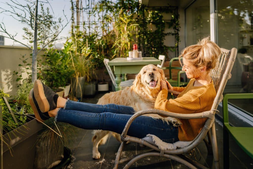 A woman pets her dog on the balcony of her apartment.