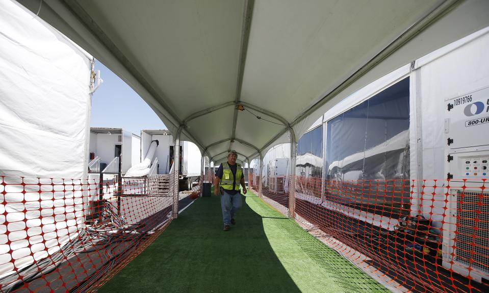 Workers put the finishing touches as the U.S. Border Patrol unveiled a new 500-person tent facility during a media tour Friday, June 28, 2019, in Yuma, Ariz. The facility will be used to process detained immigrant children and families who cross the U.S. border. The Border Patrol says it will start placing families there on Friday night. (AP Photo/Ross D. Franklin)