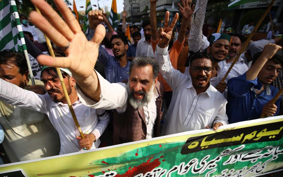 People hold flags of Pakistani-administered Kashmir as they participate in a protest march to mark the first anniversary of India abrogating the semi-autonomous status of the disputed region - Shutterstock