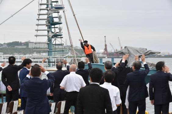 A fisherman waves to well-wishers on a whaling ship as they depart from a port in Kushiro, Hokkaido Prefecture on July 1, 2019 (AFP)