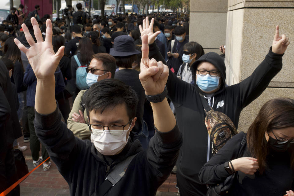 Supporters gesture as many people queue up outside a court to try to get in for a hearing in Hong Kong Monday, March 1, 2021. Pro-democracy activists detained by police on Sunday on charges of conspiracy to commit subversion under the sweeping national security law, are expected to appear in court. (AP Photo/Vincent Yu)