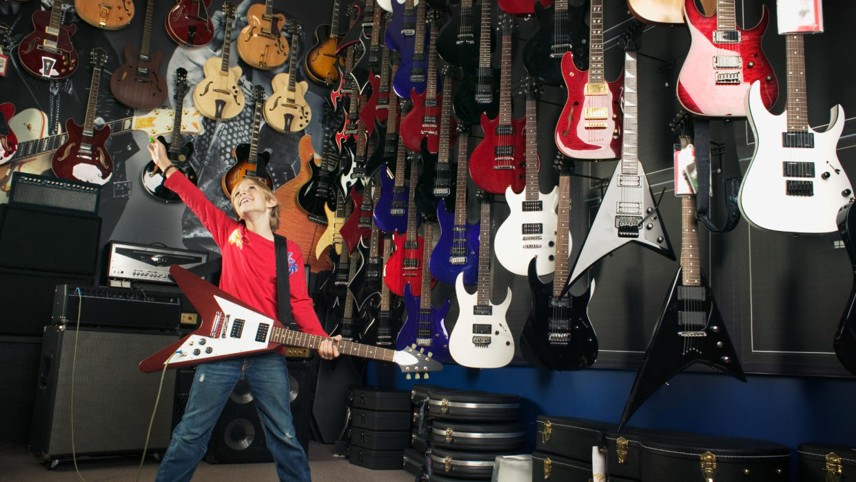  Kid in a guitar store playing a Gibson Flying V. 