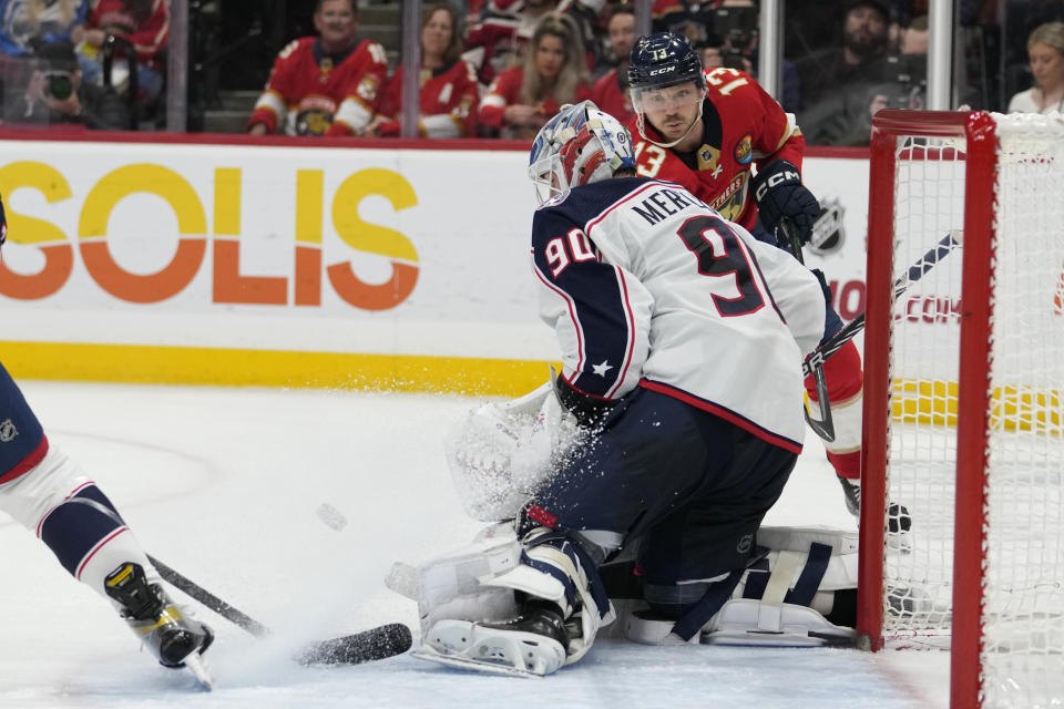 Columbus Blue Jackets goaltender Elvis Merzlikins (90) defends a shot on the goal by Florida Panthers center Sam Reinhart (13) during the second period of an NHL hockey game, Tuesday, Dec. 13, 2022, in Sunrise, Fla. (AP Photo/Lynne Sladky)