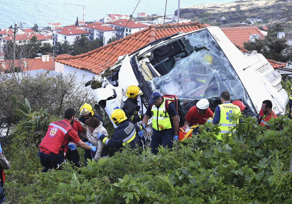 Varios socorristas asisten a víctimas de un autobús turístico que se salió de una carretera y se fue por una cuesta hasta estrellarse al menos contra una casa en la localidad de Canico, en la isla portuguesa de Madeira, el miércoles 17 de abril de 2019. En el accidente perecieron 29 turistas alemanes, según las autoridades. (Rui Silva/Aspress/Global Imagens via AP)