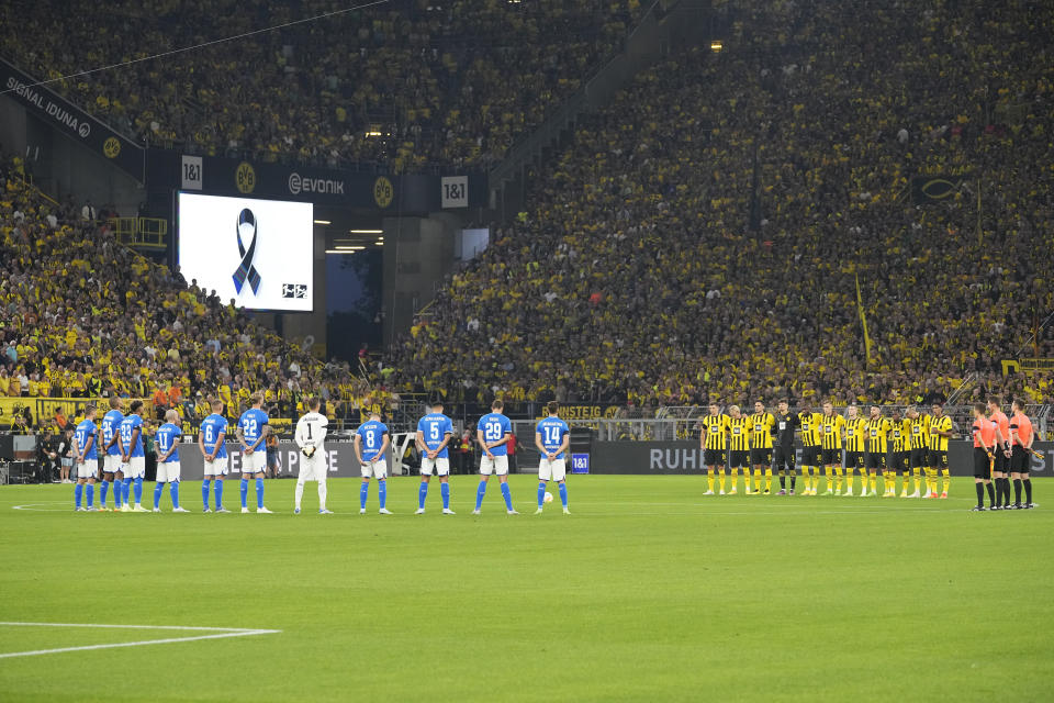 Team players and referees, right, stand during a minute of silence for the victims of the terrorist attack at the Olympic Games in Munich in 1972, prior the German Bundesliga soccer match between Borussia Dortmund and TSG 1899 Hoffenheim in Dortmund, Germany, Friday, Sept. 2, 2022. Eleven athletes from Israel and one German police officer were killed 50 years ago in the terrorist attack during the 1972 Olympic Games in Munich. (AP Photo/Martin Meissner)