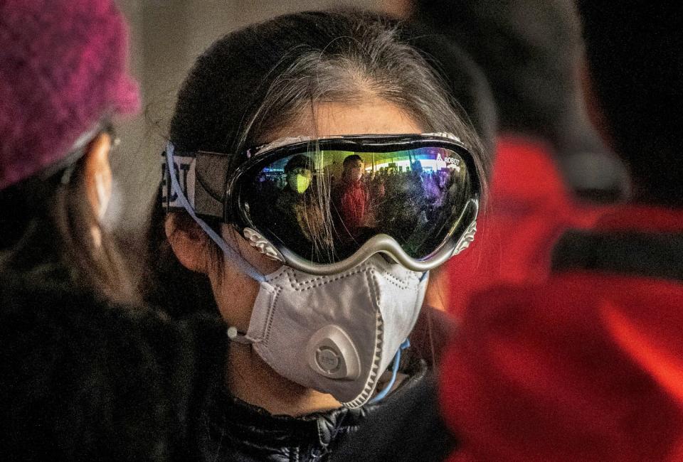 CHINA: A woman wears ski goggles and a protective mask as she checks in to a flight at Beijing Capital Airport.