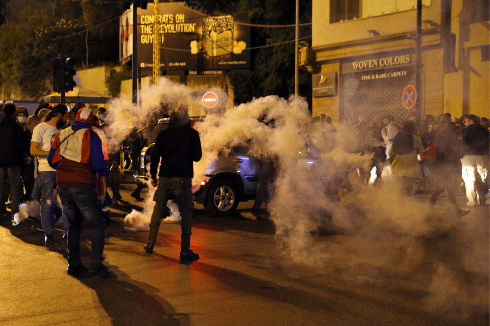 Protesters are seen surrounded by tear gas that was fired towards them by Lebanese riot police during an anti-government protest in Beirut, Lebanon, Wednesday, Dec. 4, 2019. Protesters have been holding demonstrations since Oct. 17 demanding an end to corruption and mismanagement by the political elite that has ruled the country for three decades. (AP Photo/Bilal Hussein)