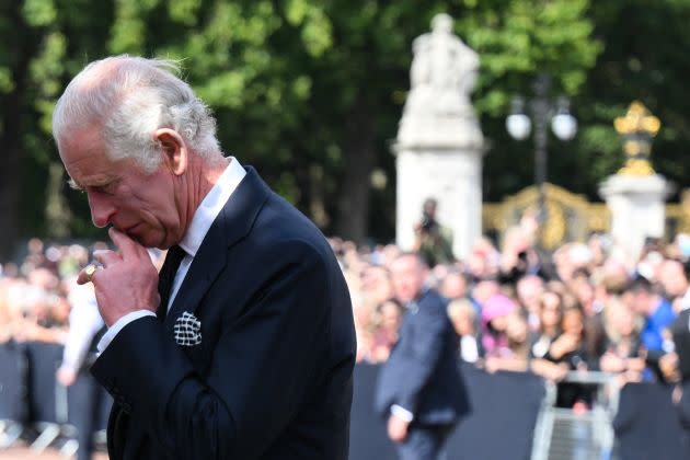King Charles III looks at floral tributes left outside of Buckingham Palace in London, on Sep. 9, a day after Queen Elizabeth II died at the age of 96. (Photo: DANIEL LEAL via Getty Images)