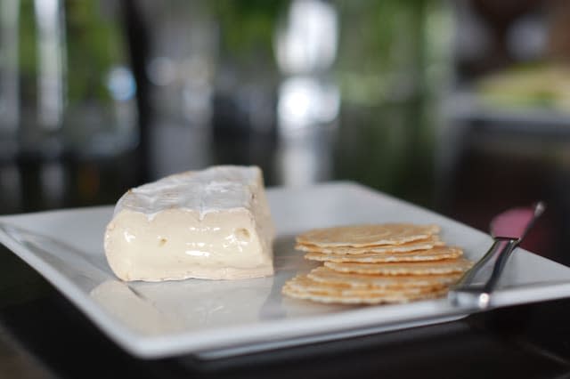 Brie cheese and crackers with knife on white plate.