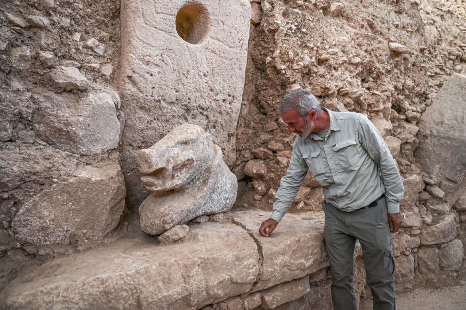 Professor and director of the department of prehistory at Istanbul University Necmi Karul shows the 1.20 m long, 70 cm high newly found polychrome wild boar at the archaeological site of Gobeklitepe, southeastern Turkey on October 9, 2023. With its red eyes and teeth and black-and-white body, this 11,000-year-old wild pig is "the first colored sculpture from this period discovered to date."<p>OZAN KOSE/Getty Images</p>