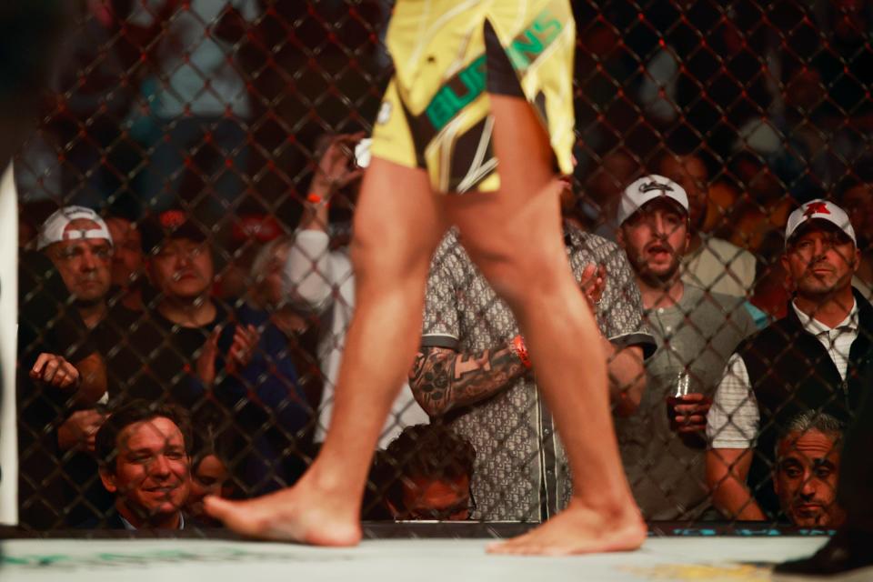 Florida Governor Ron DeSantis, left, sits ringside to watch as Gilbert Burns passes to take on Khamzat Chimaev Saturday, April 9, 2022 during UFC 273 at VyStar Veterans Memorial Arena in Jacksonville. [Corey Perrine/Florida Times-Union]