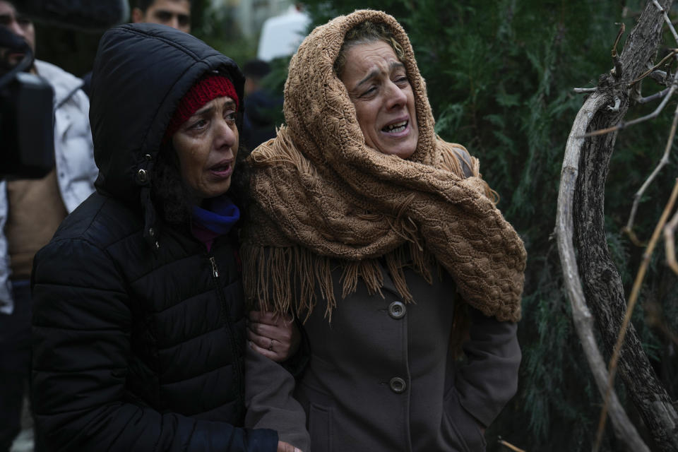 FILE - Women cry as they watch while the emergency teams search for people in the rubble of a destroyed building in Adana, Turkey, Feb. 6, 2023. A year after the devastating 7.8 magnitude earthquake struck southern Turkey and northwestern Syria, a massive rebuilding effort is still trudging along. The quake caused widespread destruction and the loss of over 59,000 lives. (AP Photo/Khalil Hamra, File)