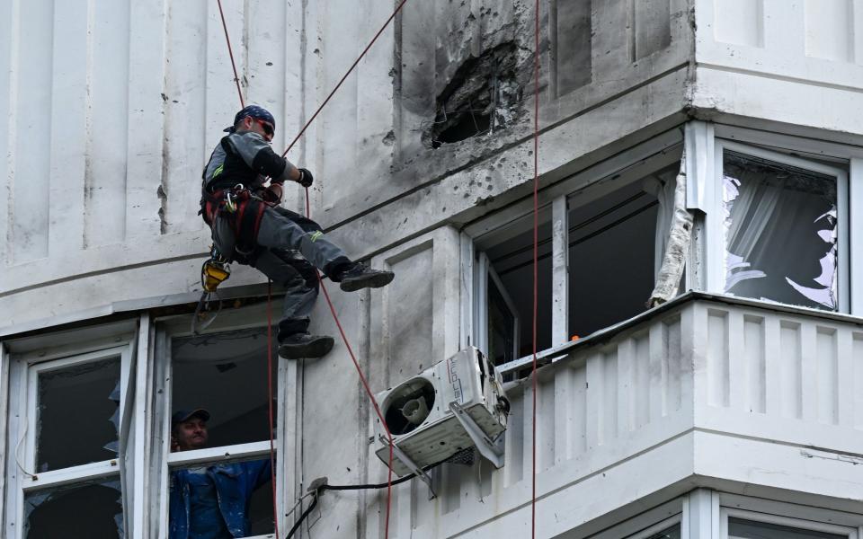 A specialist inspects the damaged facade of a multi-storey