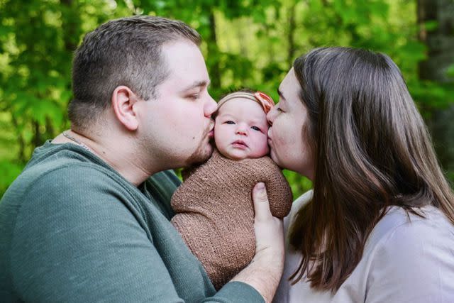 <p>Courtesy of Kaylee and Landon Doss</p> Landon Doss and Kaylee Doss kissing daughter Rowan