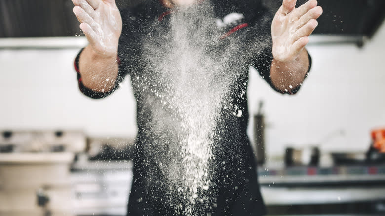 a chef dropping flour onto work surface