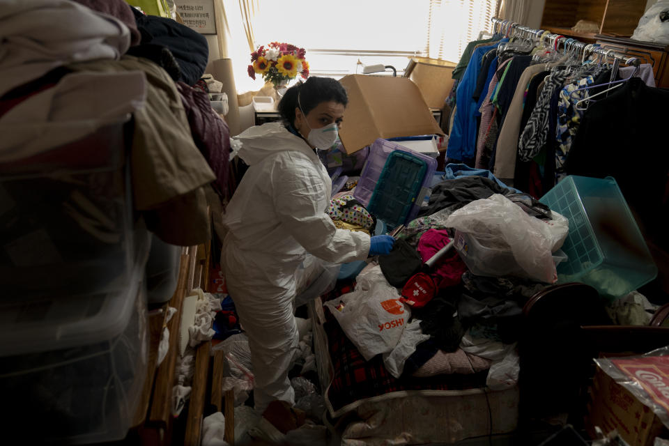 Arusyak Martirosyan, an investigator with the Los Angeles County Public Administrator's office, searches through a cluttered one-bedroom apartment in Los Angeles, Thursday, Nov. 16, 2023, for clues that might lead to finding family members or relatives of a tenant who died in the hospital with no apparent next of kin. (AP Photo/Jae C. Hong)