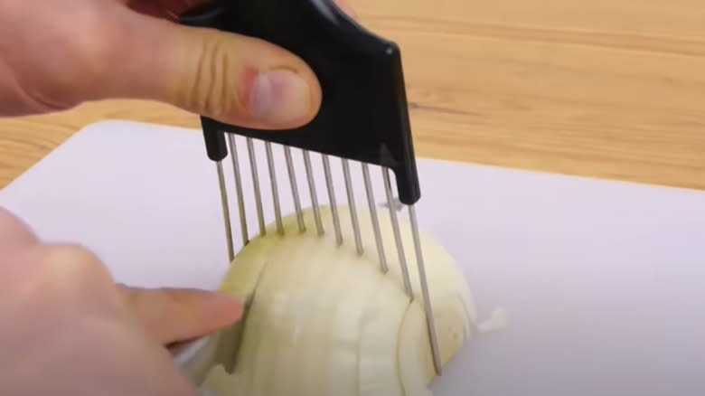 Person chopping onion held by hair pick