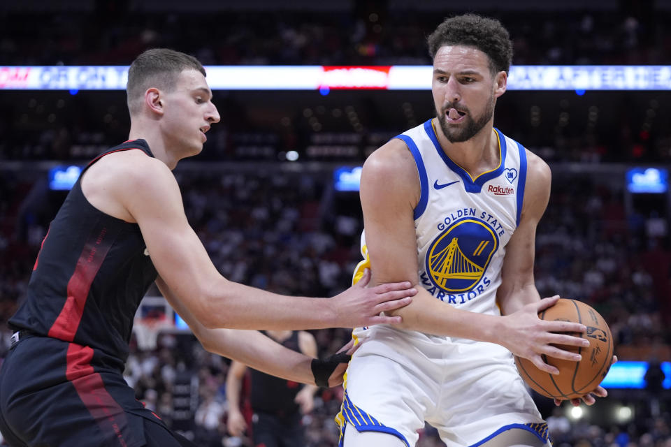 Golden State Warriors guard Klay Thompson (11) looks for an opening past Miami Heat forward Nikola Jovic (5) during the first half of an NBA basketball game, Tuesday, March 26, 2024, in Miami. (AP Photo/Wilfredo Lee)