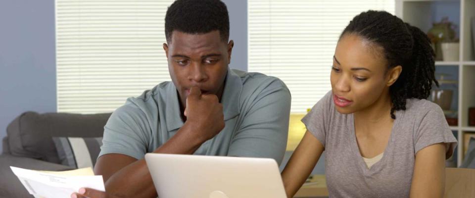 Worried young African American couple looking through bills online