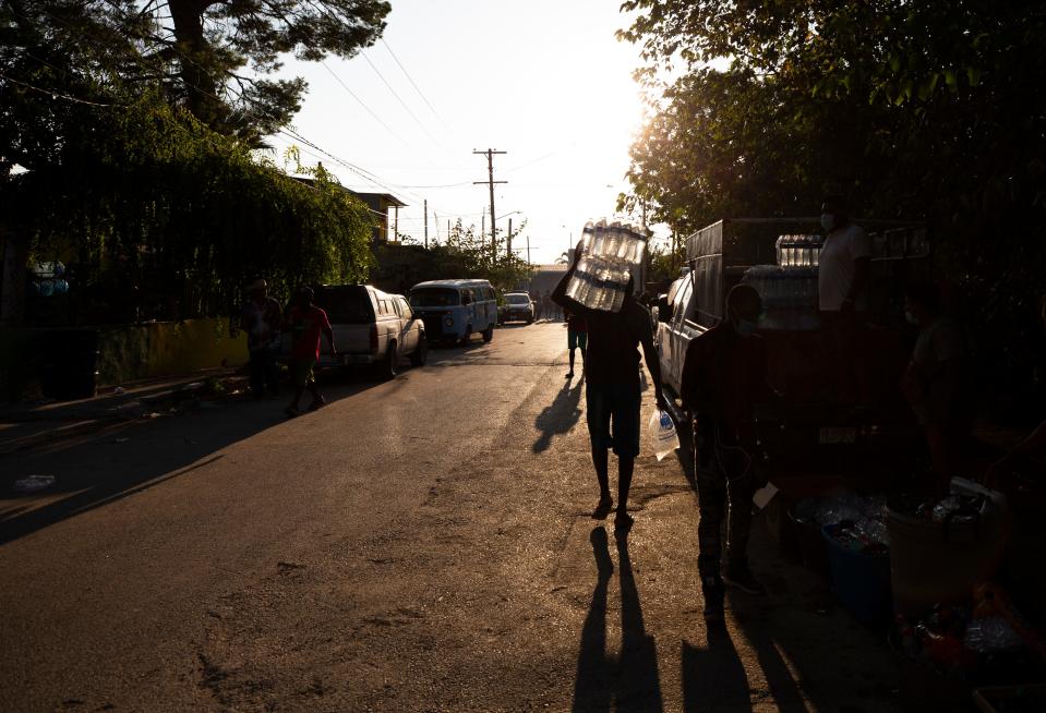 A Haitian migrants carries water back towards the Rio Grande in Ciudad Acuna as migrants buy water and food to carry back into a camp on the U.S. side in Del Rio, Texas.