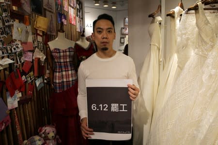 Alan Li poses with a sign reading "June 12 Strike" inside his clothing store Alca&Co as he decided to close the business for a day in protest against the proposed extradition bill in Hong Kong