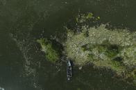 FILE - A boat moves through garbage floating on the basin of the Cerron Grande hydroelectric dam near Potonico, El Salvador, Sept. 25, 2022. More than 2,000 experts plan to wrap up early negotiations Friday, Dec. 2, on plastic pollution at one of the largest global gatherings ever to address the crisis. (AP Photo/Salvador Melendez, File)