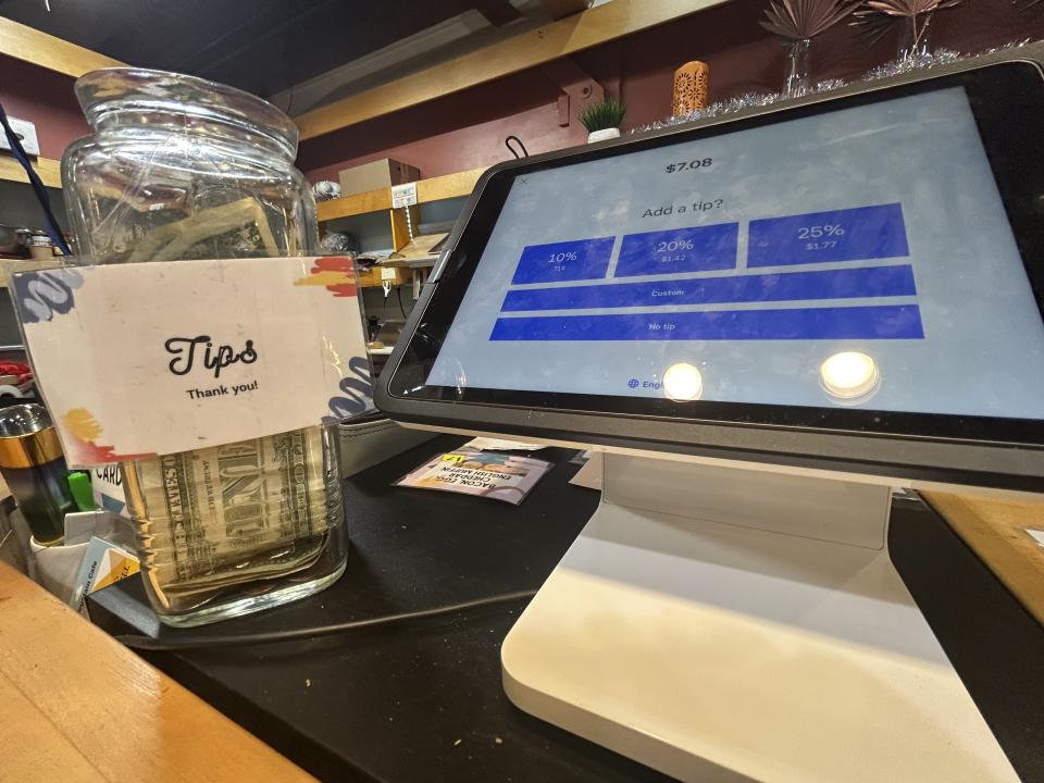 A glass tip jar, left, appears next to a point-of-sale payment system screen displaying tip options at a coffee shop in Waitsfield, Vt., on Wednesday, Nov. 29, 2023. (AP Photo/Carolyn Lessard)