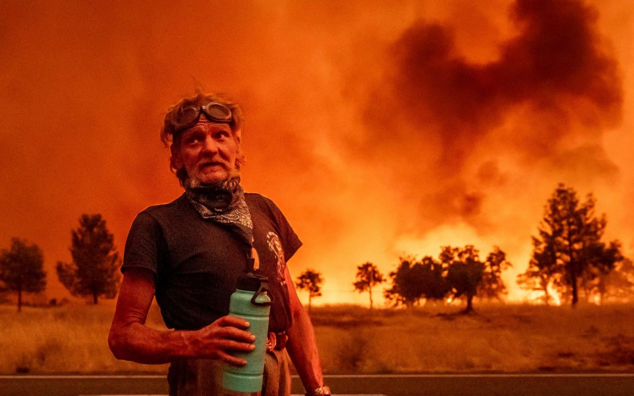 A man pauses to drink water while evacuating near Paynes Creek in Tehama County, California