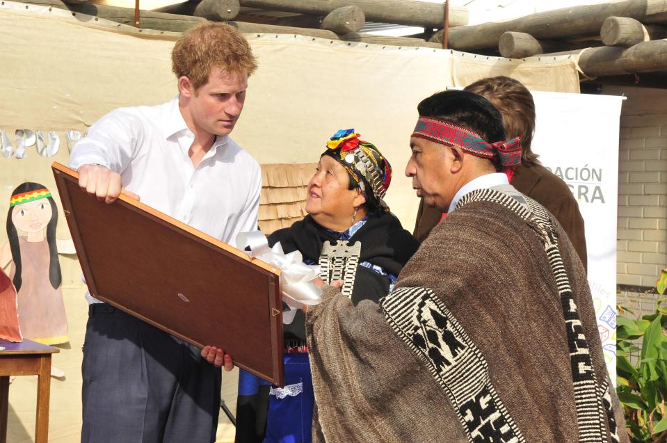 Mapuche people explain the meaning behind drawings presented as a gift to Britain's Prince Harry during a visit to Integra Foundation, a daycare center for at-risk children, in Santiago