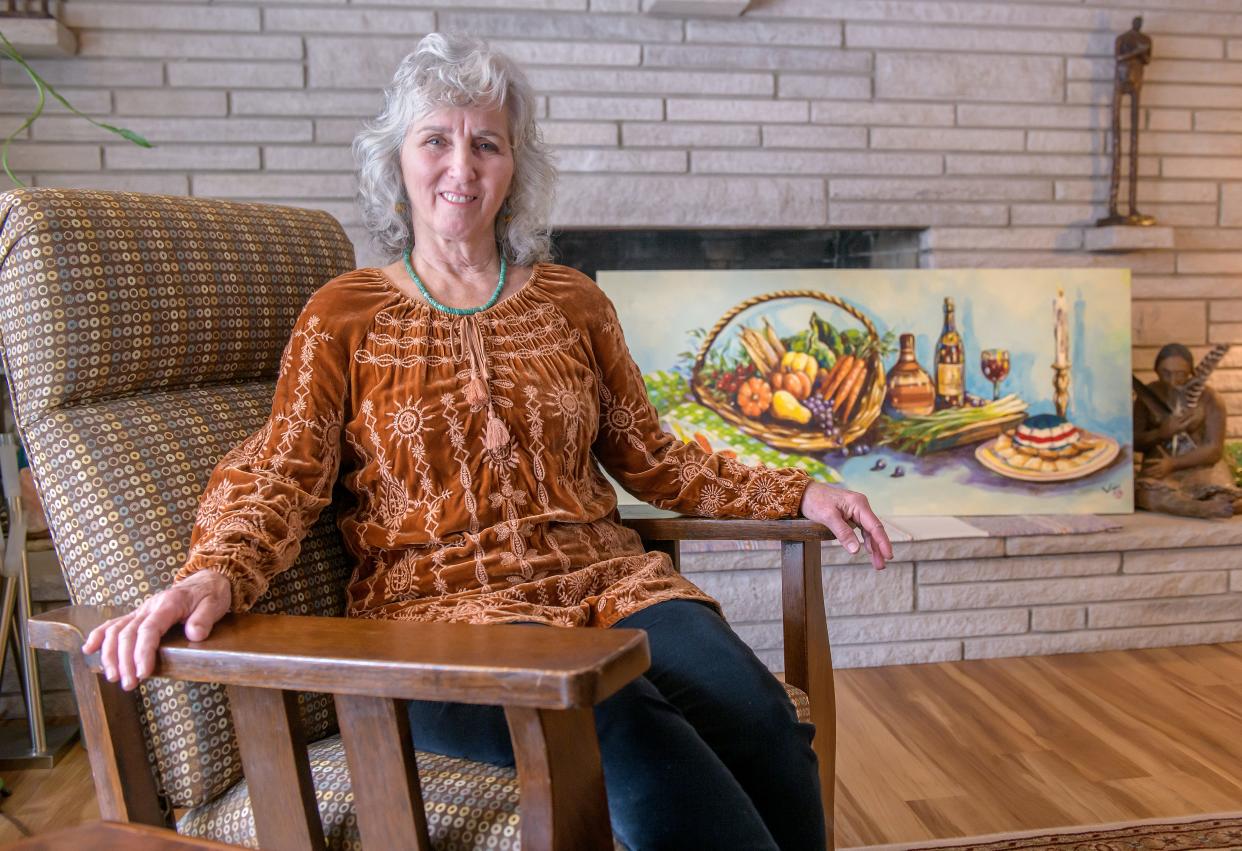 Connie Randall sits next to a painting by late Peoria artist Vin Luong that used to hang at her catering business A Matter of Taste on Glen Avenue in Peoria Heights. Randall started the business in 1979 and recently shut down the shop and retired.