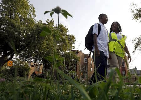 Safe Passage worker Irene Fonder walks with a Sherwood Elementary School student in the Englewood neighborhood in Chicago, Illinois, United States, September 8, 2015. REUTERS/Jim Young