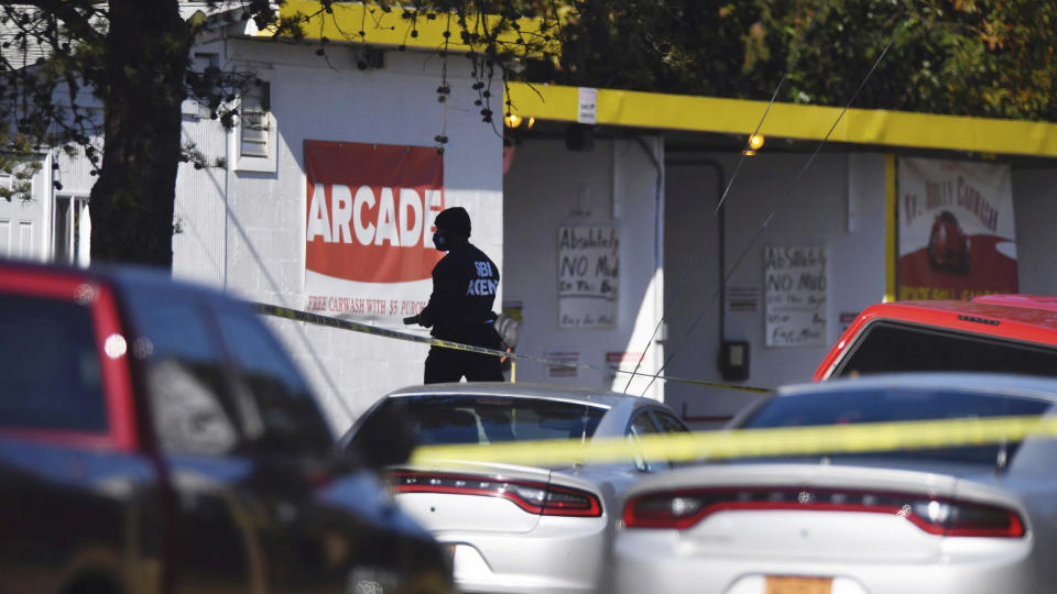 Law enforcement investigators survey the scene of a shooting at a car wash in the Belmont area of Gaston County, N.C., Friday, Dec. 11, 2020. A North Carolina police officer has been killed in a shootout while responding to a breaking and entering call early Friday morning. Authorities say Mount Holly police officer Tyler Herndon was shot during a shootout between the breaking and entering suspect and police officers. (David Foster/The News & Observer via AP)