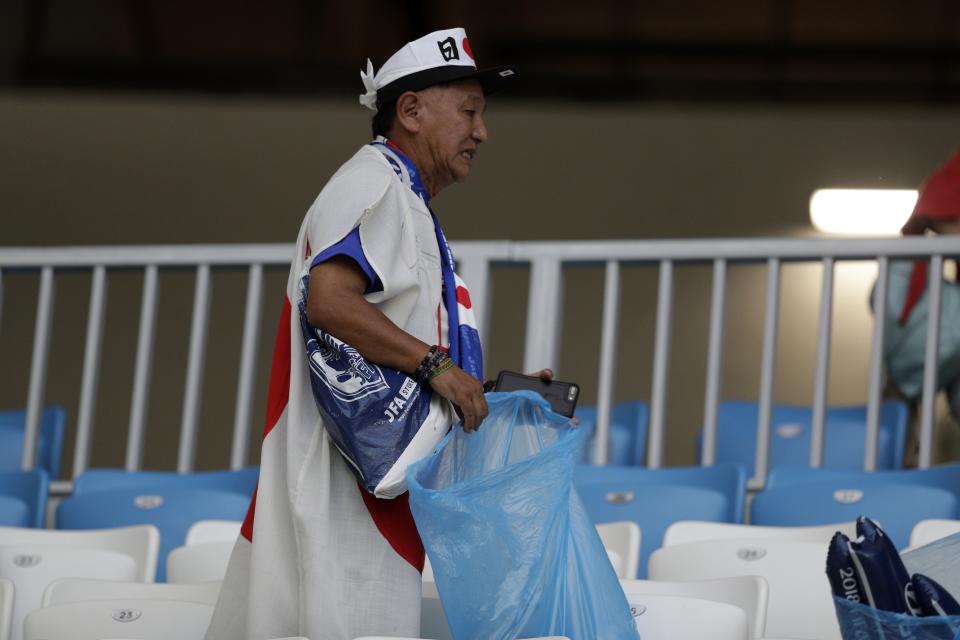 <p>A Japanese fan collects garbage from the seats after their clash against Poland in Volgograd. </p>