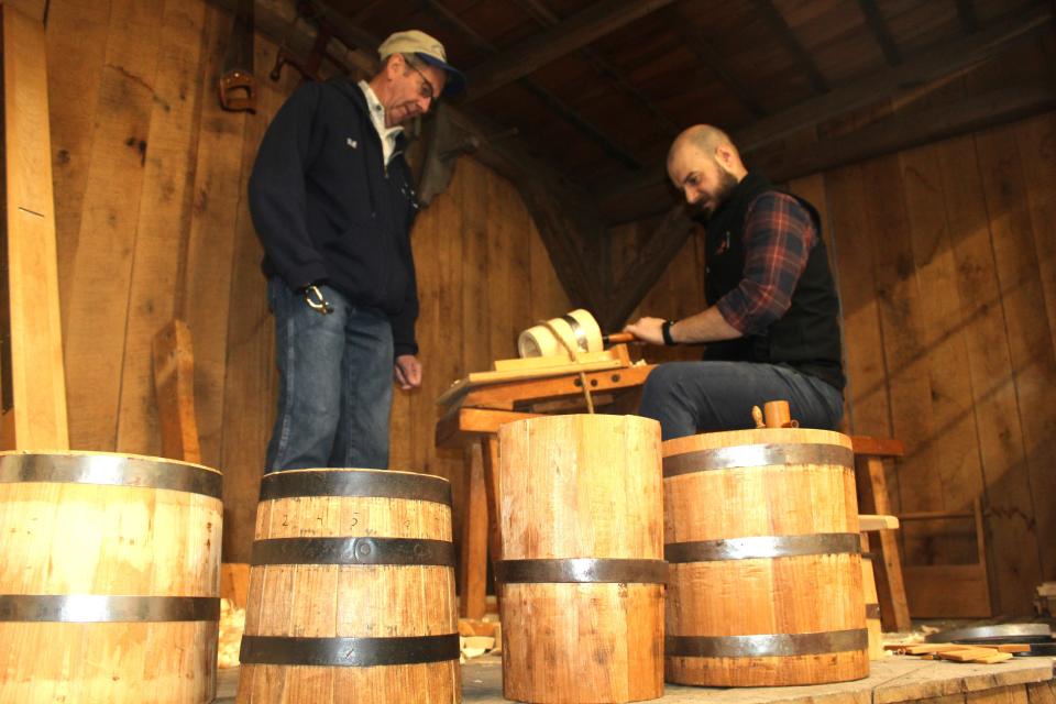 Bill Blough of Jenner Township watches Jacob Miller, curator for the historical society, as he demonstrates coopering in the new Pa. Maple Museum at Hoffman Hall on the grounds of the Somerset Historical Center.