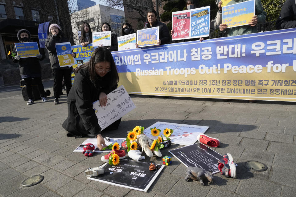 A protester places a flower to pay tribute to children killed in Russia's war against Ukraine during a rally to mark the one-year anniversary of Russia's invasion of Ukraine, near the Russian Embassy in Seoul, South Korea, Friday, Feb. 24, 2023. (AP Photo/Ahn Young-joon)