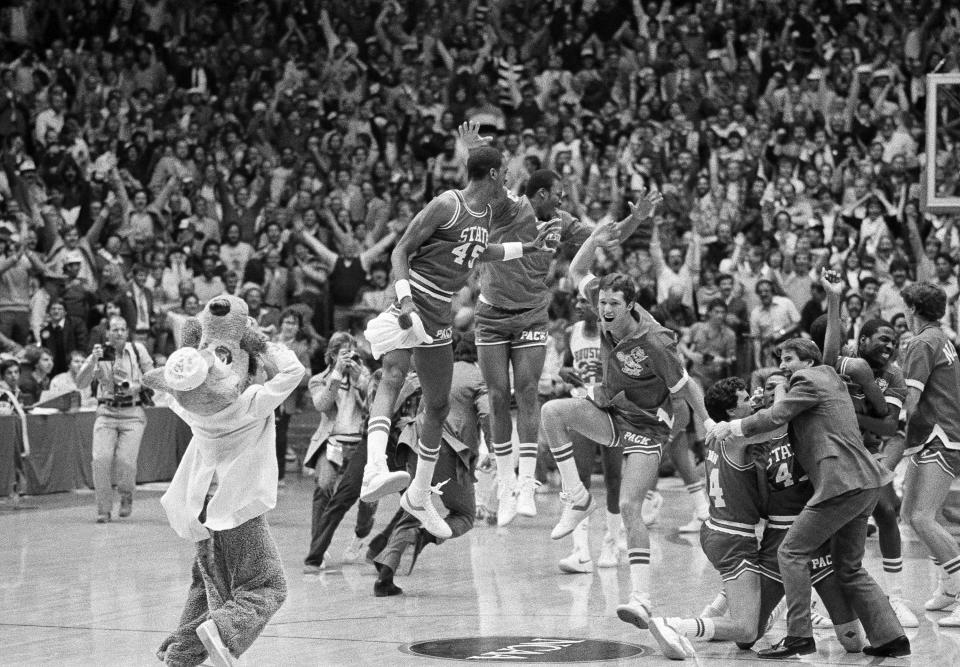 FILE - A high jumping Cozell McQueen (45), left center, and teammates celebrate defeating Houston in the NCAA college basketball championship game in Albuquerque, N.M., on April 4, 1983. How well do you know the men’s NCAA Tournament? Try this AP trivia quiz about the history of March Madness without help from search engines. (AP Photo/File)